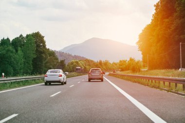 Dağların yakınındaki kırsal bir otoyolda arabalar.