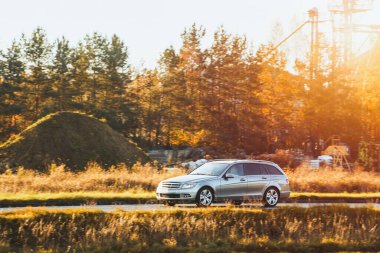 Modern aile arabası ağaçların yanında gidiyor.