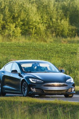 Gelecekçi hibrit araba manzaralı yolda ilerliyor.