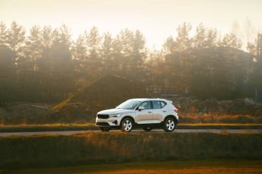 Kırsal yolda sonbahar ağaçlı bir SUV.