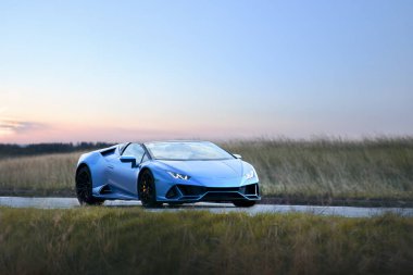 Gün batımında manzaralı yolda üstü açık bir araç.