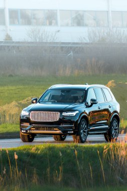 Modern expensive SUV on countryside road during sunset