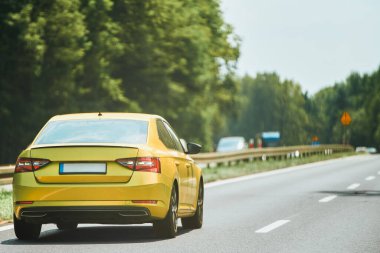 Sarı araba otoyolda gidiyor.