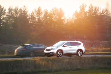 Güneşli bir kır yolunda giden SUV.