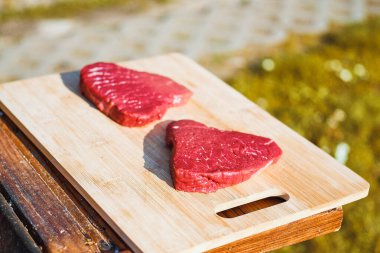 Metal ızgarada pişmemiş biftek ve kömür.