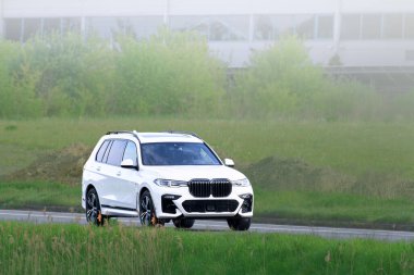 Araba orman ve yeşil tepenin yanından geçiyor.