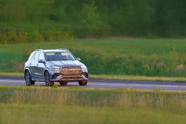 Huzurlu yolda ağaçların yanında giden SUV.