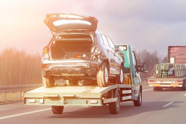 Otobanda hasarlı araba taşıyan bir çekici.