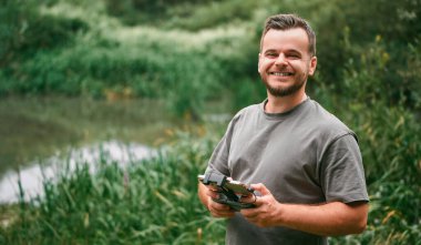 Yeşil alanda uzaktan kumandalı bir uçak tutan adam..