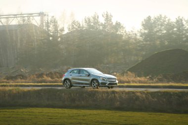 Günbatımında şehir yolunda üst sınıf bir araba.