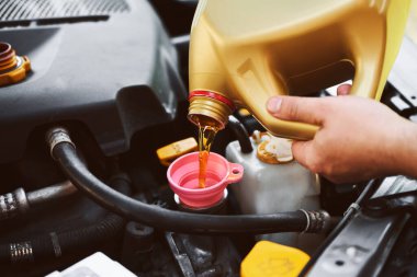 Tamirci araba motoruna sentetik yağ ekliyor
