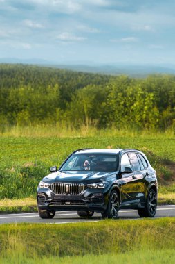 Manzaralı bir otoyolda hızlı giden bir SUV.