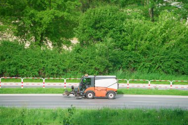 Yeşil yol kenarındaki sokak temizleme makinesi.