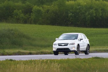 Küçük Japon SUV manzaralı kırsal alanda sürüyor.