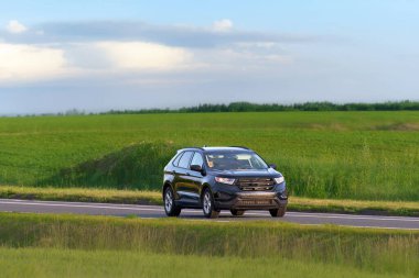 Manzaralı bir otoyolda hızlı giden bir SUV.