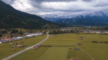 İlkbaharda dramatik bulutlu gökyüzünün altında karla kaplanmış görkemli Bavyera Alpleri
