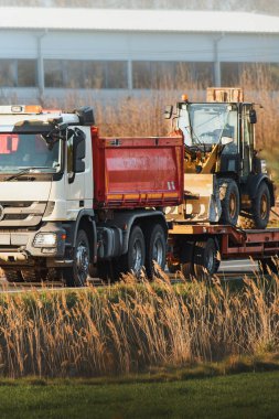 İnşaat alanının yanındaki kamyonda kürekle buldozer.