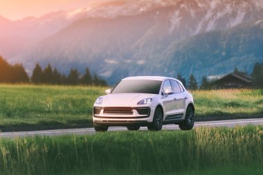 Gün batımında yeşil araziden geçen SUV