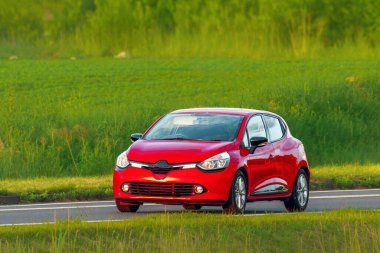 Modern hatchback boş asfalt yolda gidiyor.