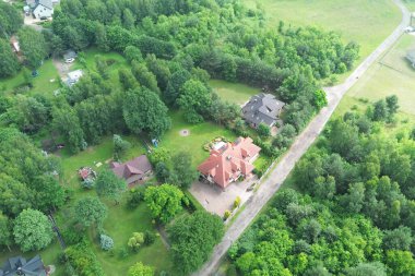 Lüks bir evin insansız hava aracı görüntüsü, bahçeli, yemyeşil bir ormana kurulmuş, doğa ve mimariyi harmanlayan..