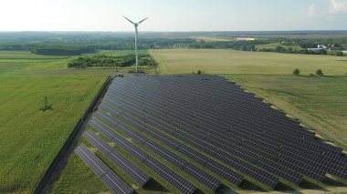Ufukta rüzgar türbini olan büyük bir güneş alanı.