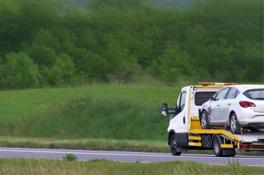 Çekici, ağır hasar görmüş arabayı yol kenarına çekiyor.