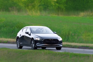 Modern hatchback boş asfalt yolda gidiyor.