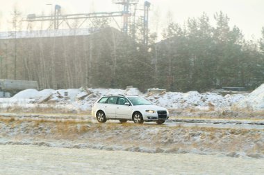 Donmuş orman manzarasında seyahat eden küçük hatchback.