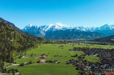 Kırmızı çatıları ve dağları olan yemyeşil bir kırsal.