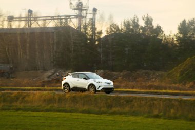 Siyah hatchback arabası şehir caddesinde geziniyor.