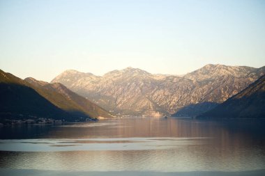 Engebeli yamaçlar ve sakin körfez altın saatinde