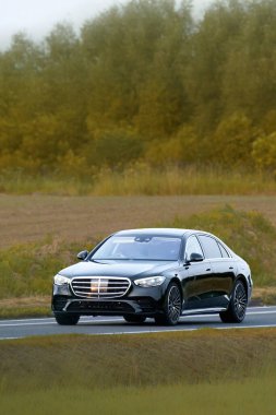 Açık yolda parlak yeni bir otomobil sürüyor.