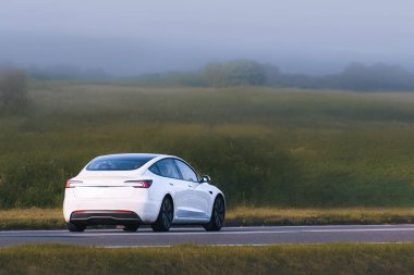 Modern hibrit araba mavi yaz gökyüzünün altında sürüyor.