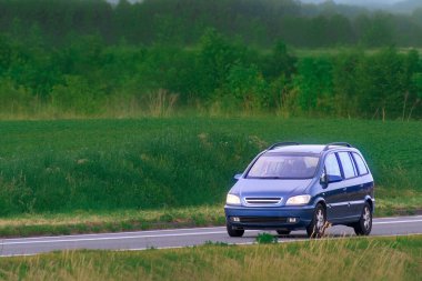 Kırsal çevre yolunda giden parlak MPV aracı