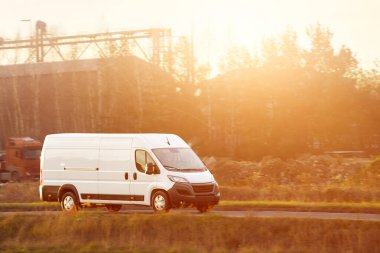 Beyaz minibüs doğada asfalt yolda ilerliyor.