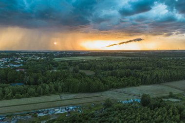 Gün batımında fırtına bulutları altında huzurlu bir köy.