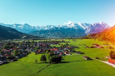 Kırmızı çatıları ve dağları olan yemyeşil bir kırsal.