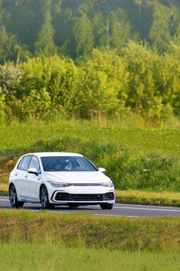 Kırsal alanda seyahat eden küçük bir hatchback arabası.