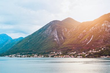 Sakin göl, yeşil tepeleri ve bulutları yansıtıyor.