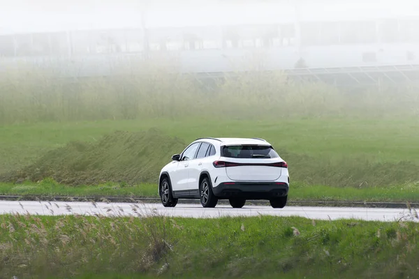 Automobile on road by rural hillside