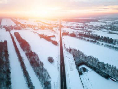 Karlı kırsalda, alacakaranlıkta bir karayolu ile