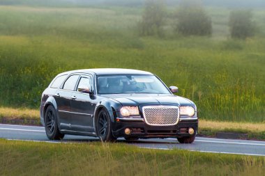 Modern bir arazi aracı manzaralı bir yolda hızla ilerliyor.