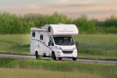 Yazın beyaz bir karavan açık bir otoyolda gidiyor.