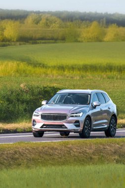 Sakin bir kırsal yolda modern bir SUV sürüyor.