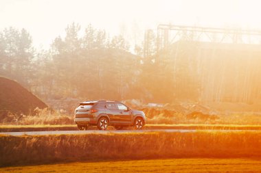 Güneşli kır yolunda modern araba sürüyor.