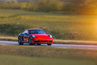 Kırmızı modern araba açık yolda gidiyor.