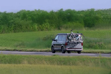 Açık kırsal yolda beyaz bir karavan sürüyor.