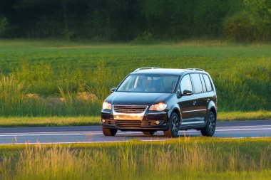 Büyük aile MPV arabası kırsal yolda ilerliyor.