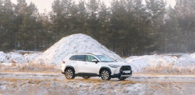 Karlı kırsal yolda SUV hareket halinde.