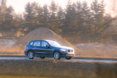 Çimenli tepeciklerin ve ağaçların yanından geçen arazi aracı